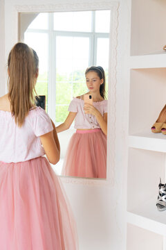 Teen girl in tutu-skirt and high-heeled shoes making selfie on smartphone