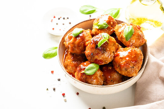 Meatballs in tomato sauce and basil on white kitchen table. Traditional recipe.