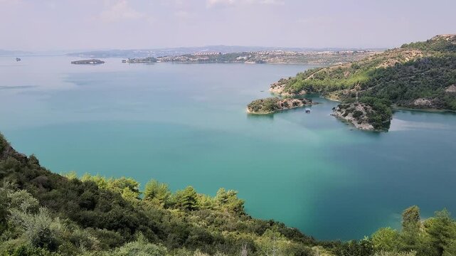 A scenic view of the northeastern inlets of Seyhan Dam Lake in Adana, T&uuml;rkiye, featuring fjord-like bays, green peninsulas, and the surrounding landscape near &Ccedil;ukurova University&rsquo;s Balcalı Campus.