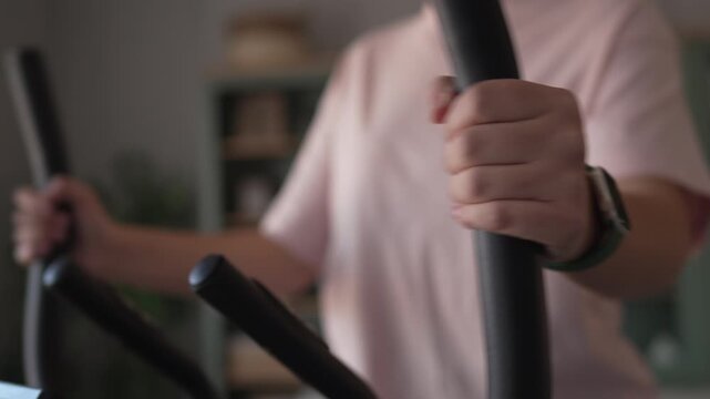 Woman with smartwatch training on elliptical machine