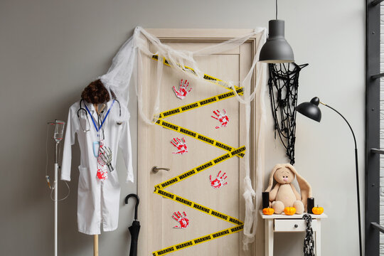 Halloween medical horror theme, doctor coat with stethoscope and IV pole decorated for spooky holiday party with warning tape and bloody handprints