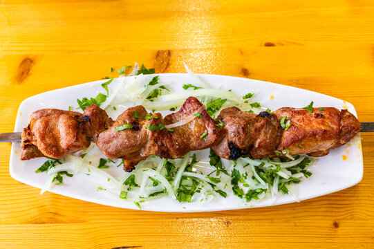 pork shashlik on steel skewer on plate on table