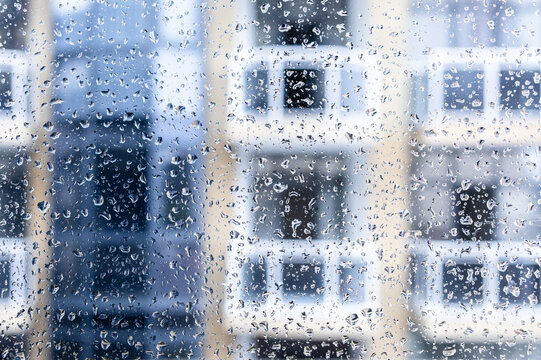 rain drops on home window glass close-up in city