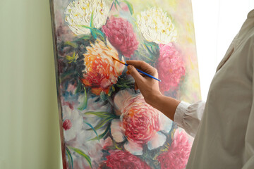 Person painting colorful floral artwork on canvas © Pixel-Shot