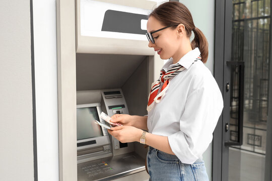 Personal finance and banking, young woman withdrawing cash from an atm machine for daily expenses and budget management in a modern urban environment