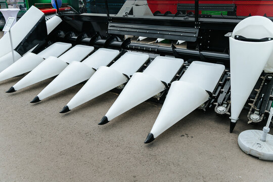 White Corn Header Attachment Stands On Concrete Floor. Agricultural Machinery Display At Industry Exhibition.