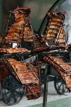 Rotating Metal Baskets Hold Seasoned Ribs Over Open Flames