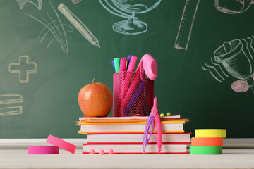 Back to school education concept, stack of books with apple and stationery supplies on a classroom chalkboard background with hand drawn chalk doodles © Pixel-Shot
