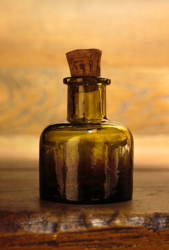 Amber glass bottle with cork stopper on rustic wooden surface. Apothecary, wellness, vintage product concept