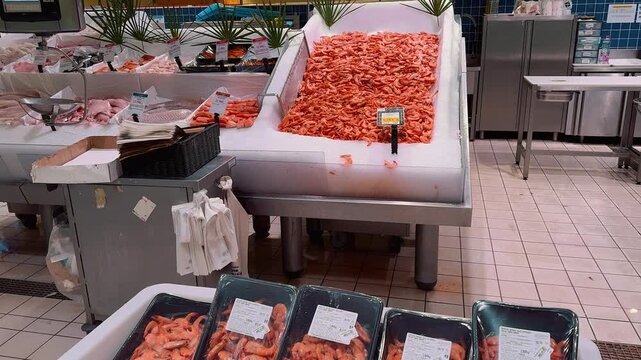 Fresh seafood assortment displayed on crushed ice at a French supermarket fish counter, showcasing whole crabs, shellfish, prawns, raw octopus, squid, and fresh salmon fillets with price tags.