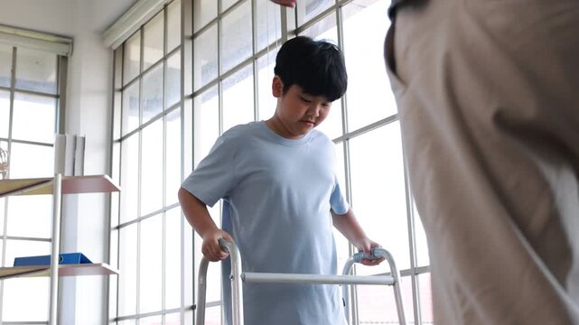 Slow motion video, orthopedic walking, Crutches Walks Confidently. Child Step in Rehabilitation with Leg Brace. Asian father helping to support his son, who has a broken ankle