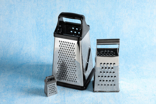 Food preparation and culinary tools, three stainless steel kitchen graters of different sizes for cooking and meal ingredients on a blue background