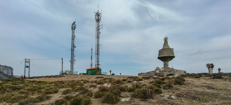 Monumento a la Virgen de Ordu&ntilde;a sobre la cima rocosa de la sierra de Sierra Salvada, junto a antenas de telecomunicaci&oacute;n bajo cielo nublado.   
