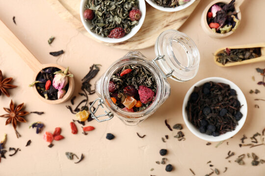 Healthy herbal tea blend, wellness and organic nutrition concept, dried fruit and flower infusion in glass jar with wooden spoons on beige background