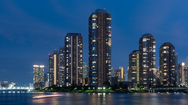 Tokyo waterfront nightscape with illuminated skyscrapers and boat light trail
船の光跡と高層ビルが映る東京の水辺の夜景