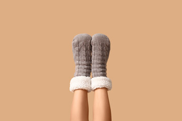 Comfort and cozy lifestyle, woman wearing warm knitted wool socks with fleece lining for winter relaxation and home wellness on a beige background © Pixel-Shot