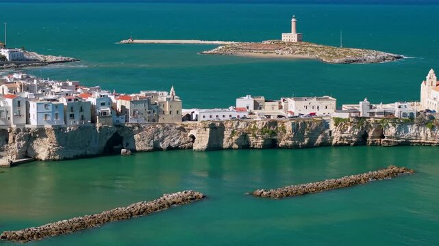 Vieste 70mm drone flyby along cliff promontory revealing San Francesco church and lighthouse on Sant Eufemia island background Gargano Puglia Italy Adriatic Sea cinematic B-roll