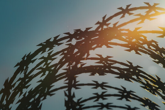 Abstract shadow pattern of intersecting star shapes against a blue sky with warm sunlight, creating a layered outdoor geometric silhouette composition