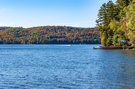 Autumn Scene on a Lake with Colorful Foliage and People Lounging on the Docks and Crusing on Motorboats