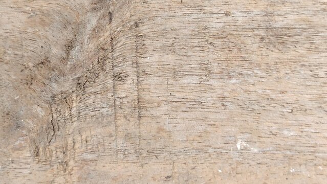 Close-up of light brown weathered wooden plank texture with natural grain, visible wood knot, and parallel surface scratches