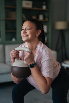 Young woman doing kettlebell squat exercise at home
