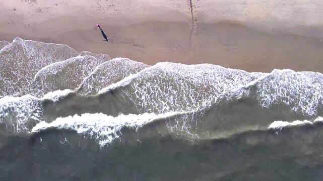Breaking waves fill the frame at the feet of a person standing on the wet sand of Chincoteague Beach, Virginia.
