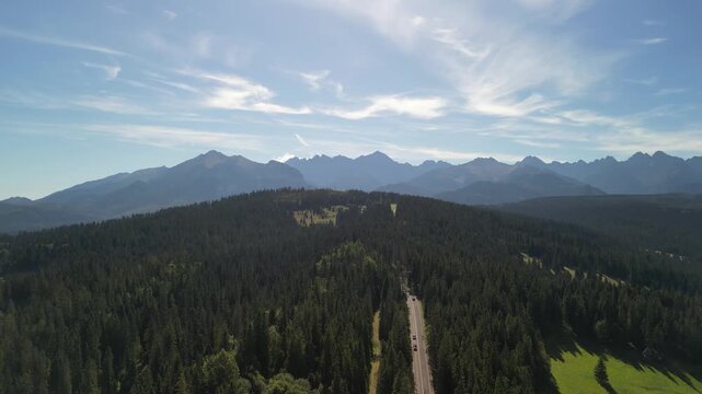 Bukowina Tatrzańska - Polska
Piękny widok na Tatry Wysokie nagrany dronem w słoneczny dzień. G&oacute;ry, chmury, słońce, pola, droga g&oacute;rska, las, Podhale.