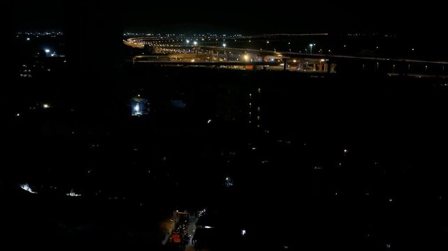 Aerial night view of Atal Setu, also known as Mumbai Trans Harbour Link, illuminated across the waterfront with connecting road infrastructure and city lights in the distance.