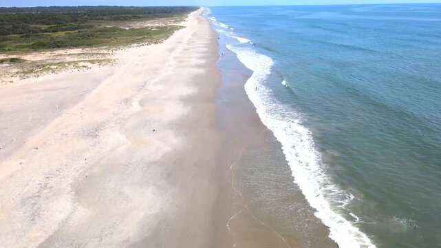 The drone follows wet sand along an open coast near the Chincoteague area.

