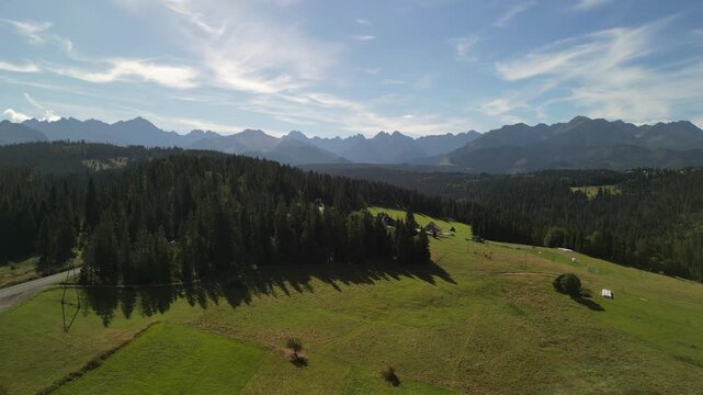 Bukowina Tatrzańska - Polska
Piękny widok na Tatry Wysokie nagrany dronem w słoneczny dzień. G&oacute;ry, chmury, słońce, pola, droga g&oacute;rska, las, Podhale.