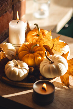 Cozy home decoration on the windowsill with little pumpkins and candles. Aromatherapy for fall season. Aesthetics, seasonal atmospheric vibes. Thanksgiving dinner decor idea.