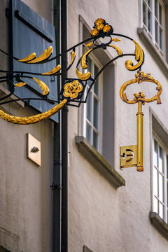Ornate golden key hanging from a wrought iron sign in Zurich, Switzerland