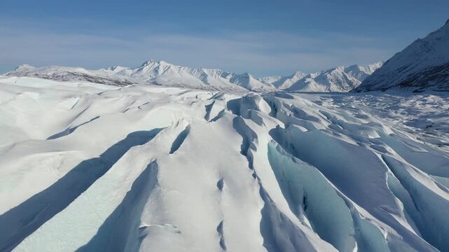 Low-Angle Drone View of Deep Blue Glacier Ice Fissures and Mountain Range