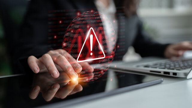 A business professional interacts with a digital warning sign on a touchscreen, highlighting concerns in cybersecurity and the importance of data protection. Gantry