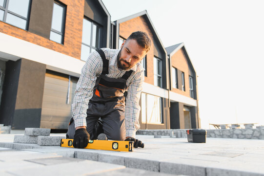 Construction worker paving outdoor area with level tool