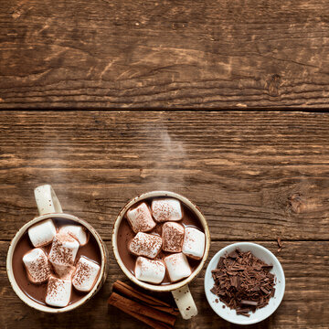 Two mugs of hot chocolate with marshmallows and chocolate shavings