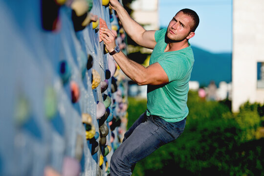 young man climbing wall rock outdoors