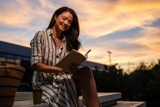 Woman enjoying reading book outdoors during sunset