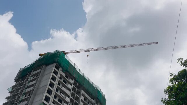 Tower Crane Rotating Above Building Under Construction Against Blue Sky