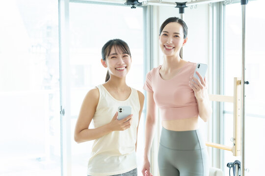 スマートフォンを持つ女性　ピラティス、ヨガ、スタジオ