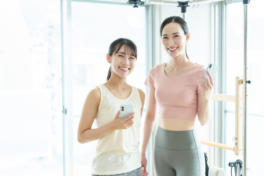 スマートフォンを持つ女性　ピラティス、ヨガ、スタジオ
