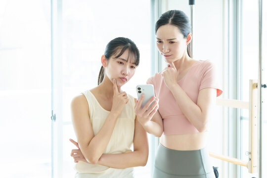 困った表情でスマートフォンを使う女性　ピラティス、ヨガ、スタジオ