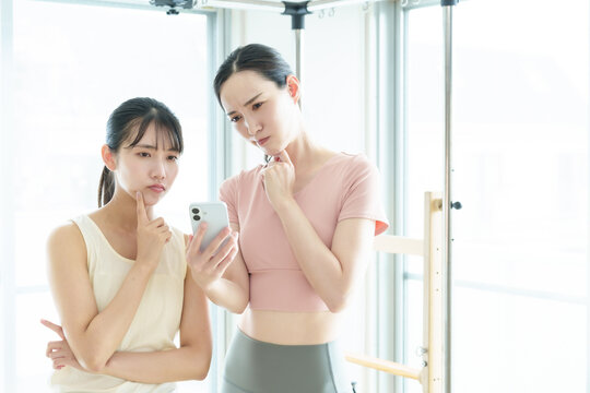 困った表情でスマートフォンを使う女性　ピラティス、ヨガ、スタジオ