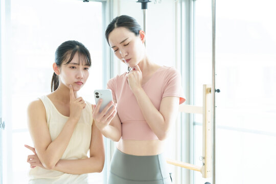困った表情でスマートフォンを使う女性　ピラティス、ヨガ、スタジオ