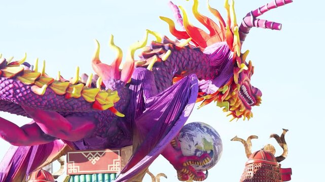 Sunny daytime parade of satirical masked carri allegorici advancing on Viareggio passeggiata mare Italy festival