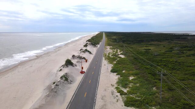 Sand dunes border a paved road along the North Carolina ocean shoreline.

