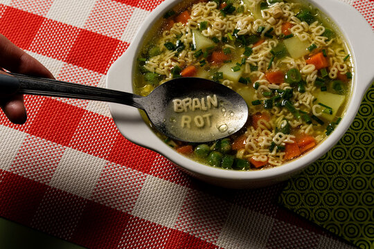 Childhood Education Crisis Concept Showing Brain Rot Spoon Scooping Alphabet Pasta Letters, highlighting the ongoing deterioration of intellectual standards in today's digital generation.