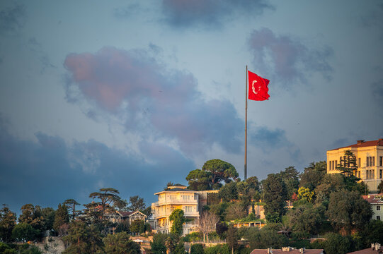 Istanbul,turkey,august 4, 2025. Turkish flag waving prominently on a hilltop above residential buildings and green trees along the bosphorus strait in istanbul, turkey