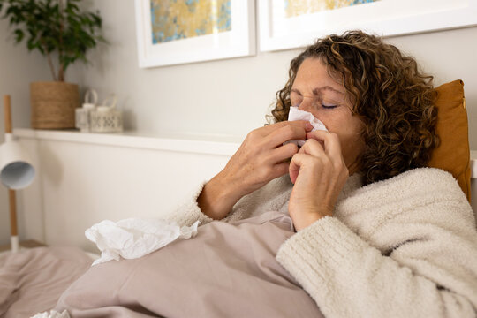 Woman blowing nose suffering from cold and flu