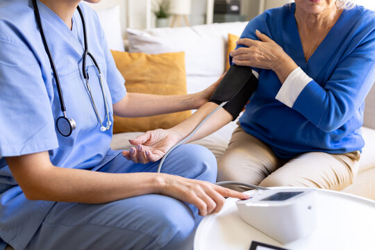 Nurse measuring blood pressure of senior woman at home visit